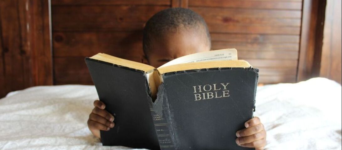 Young boy reading bible.