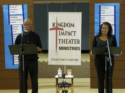 Two actors reading scripts on stage.
