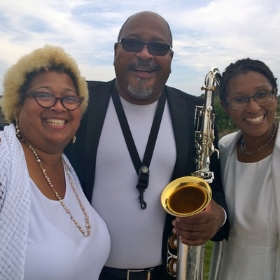 Brother and sisters smiling with saxophone.