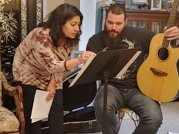 Man and women with guitar and sheet music.